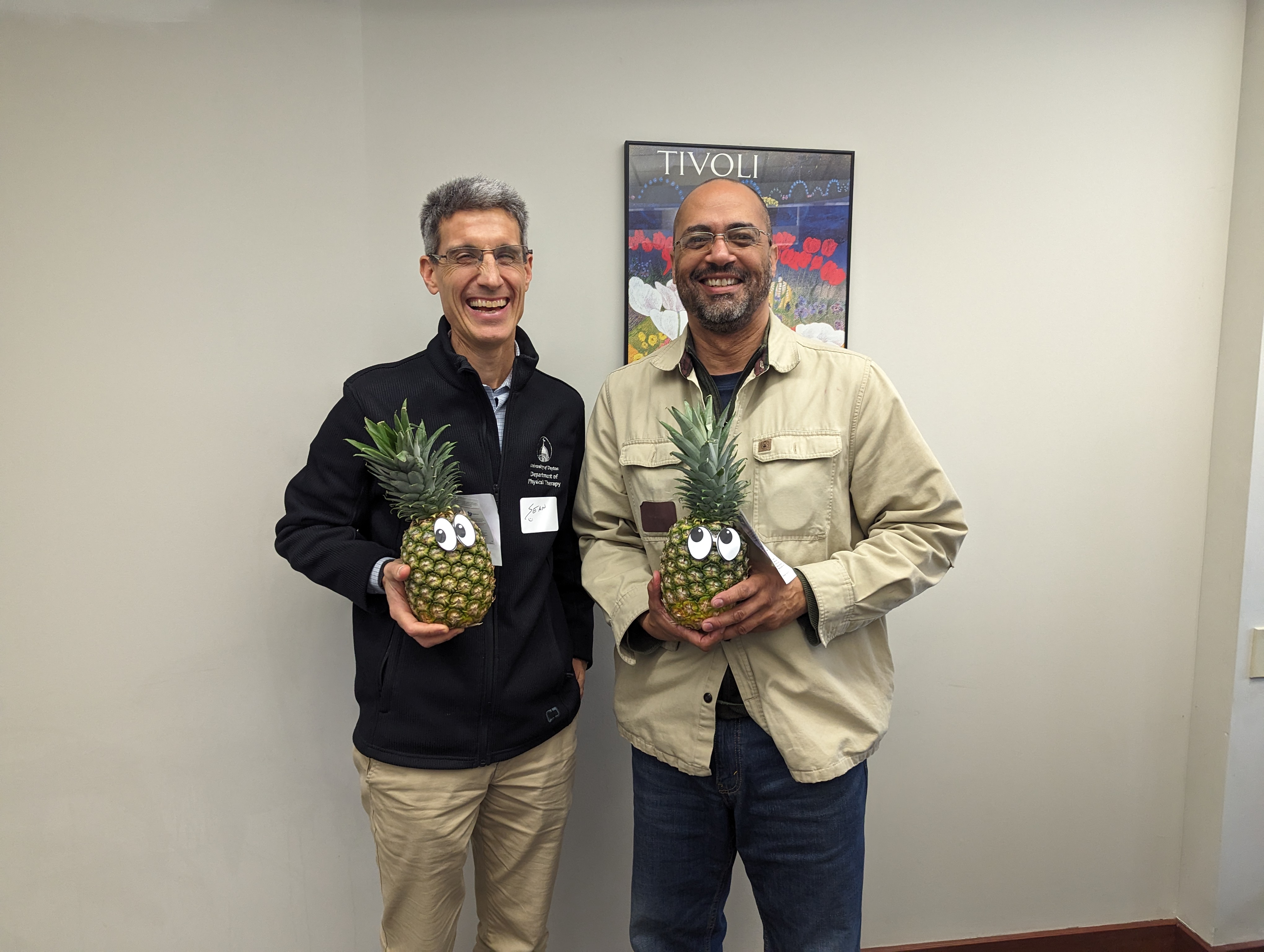 Faculty members Sean Gallivan and Robert Menafee pose with a pineapple and diploma to signify graduation from ATLS.