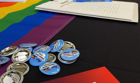 Oblique view of a table with UD LGBTQ brochures, pins, and flags.