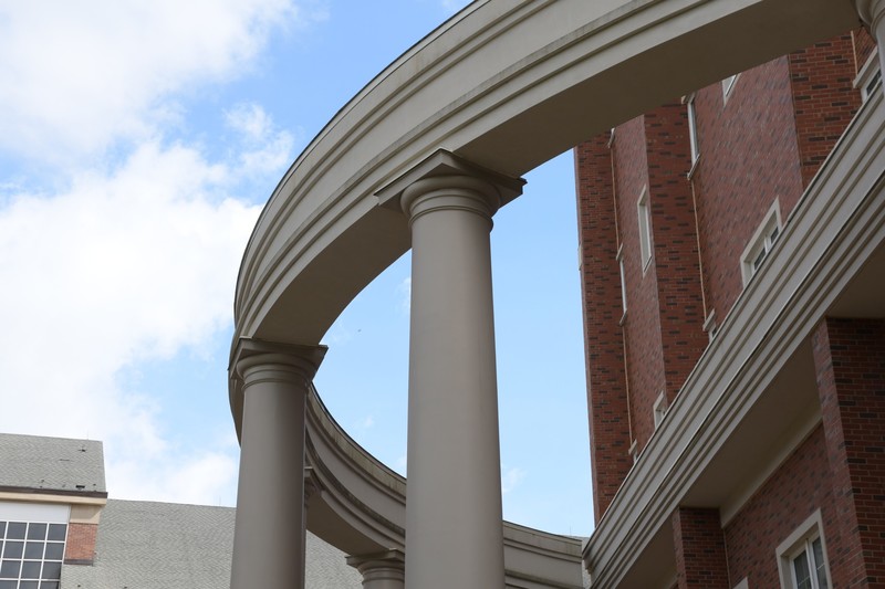 A view of the Roesch Library's west entrance, looking up at the detached semicircle of columns next to the building.